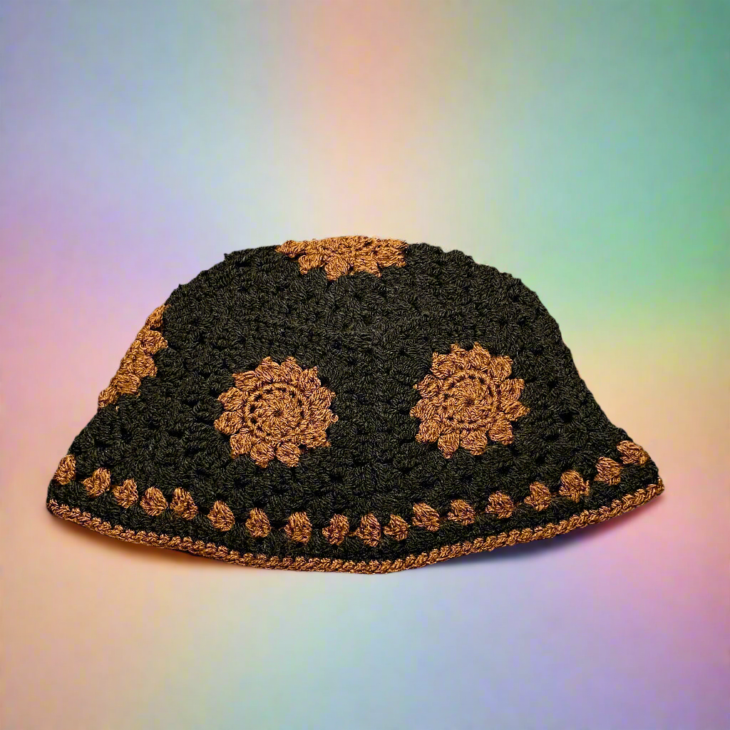 Black crocheted hat with gold floral patterns on a gradient background
