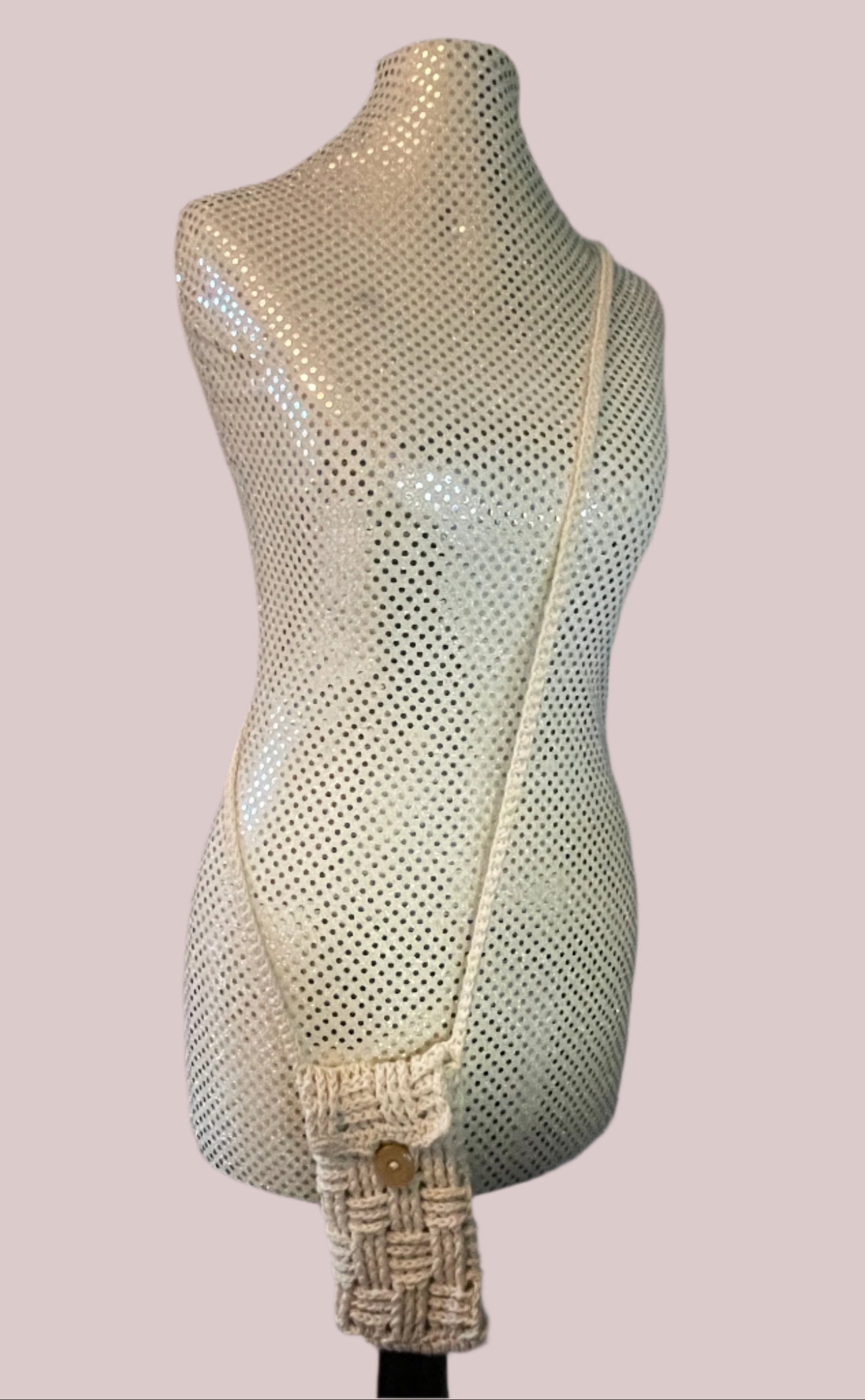A beige crochet cross body phone bag with a basket weave design displayed on a mannequin.