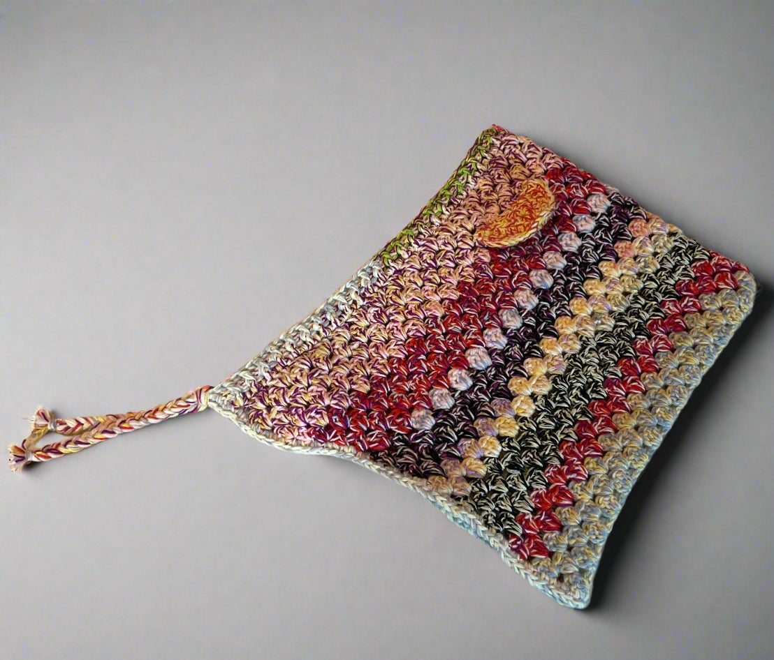 A multicolored crochet hood with ears and a loose hanging string, displayed on a neutral background.