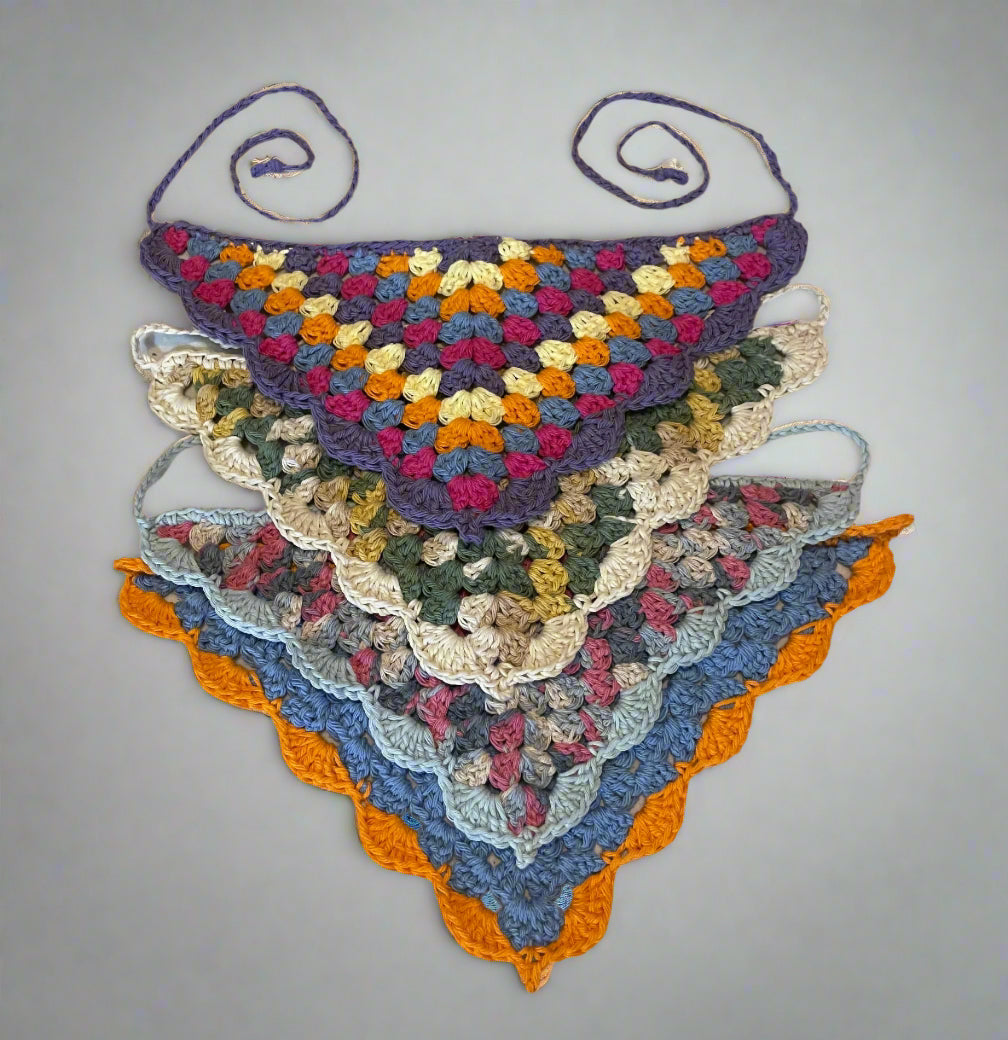 A collection of handmade crochet bandanas with shell edge in various colors laid out flat.