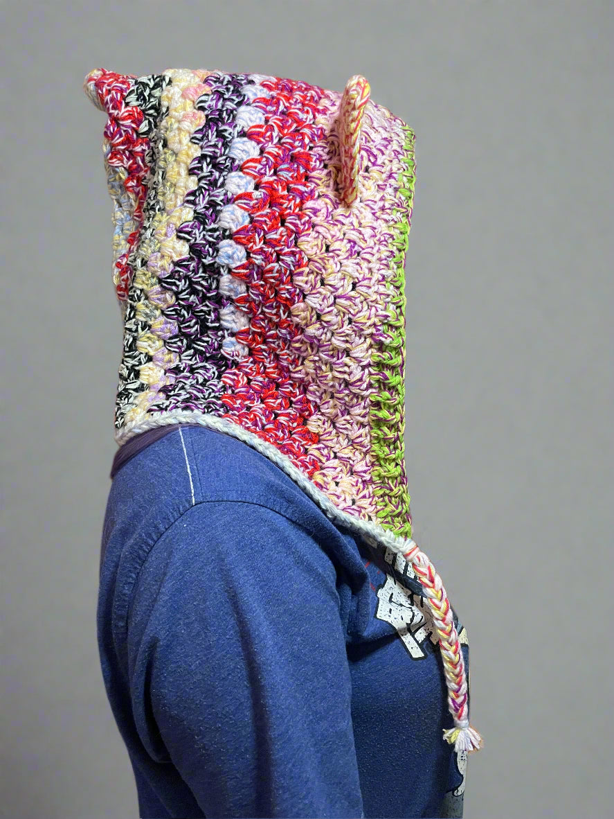 A multicolored crochet hood with ears, displayed on a mannequin.
